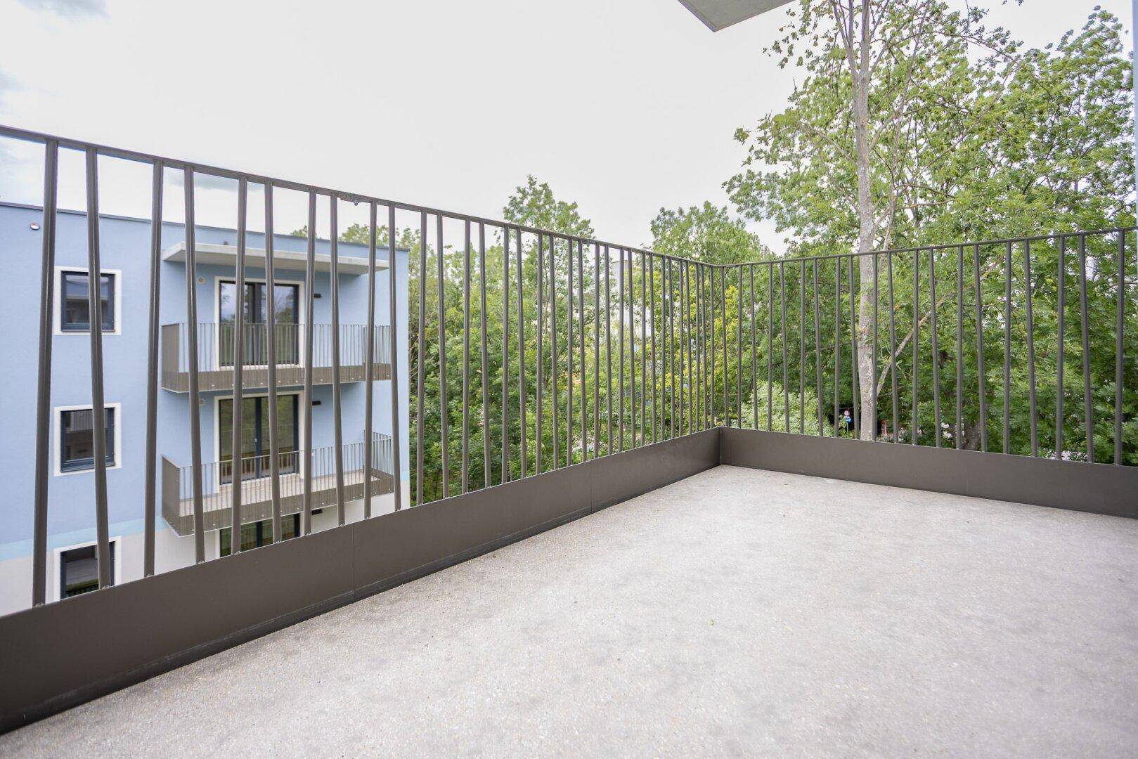 Geräumiger Balkon mit modernem Metallgeländer und Blick ins Grüne.