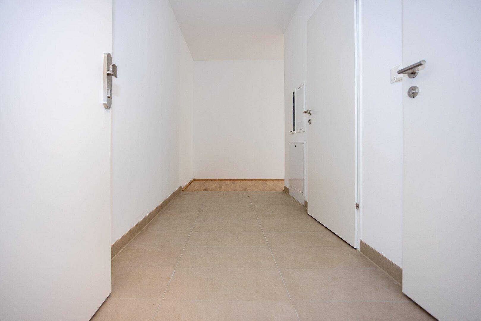 Heller Flur mit Fliesenboden und weißen Türen zu den angrenzenden Räumen.