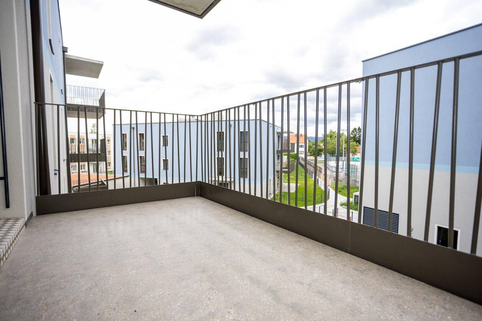 Geräumiger Balkon mit Blick auf die umliegenden Neubauten und Grünflächen.