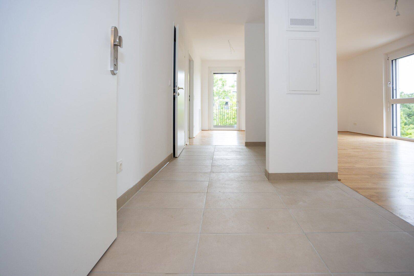 Heller Flur mit Fliesenboden und Zugang zu weiteren Räumen sowie einem Balkon.