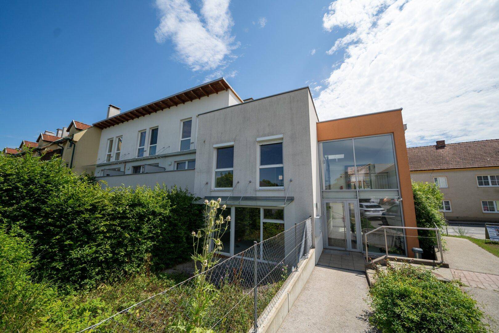 Moderne Architektur des Gebäudes mit großen Fenstern und einer Rampe für Barrierefreiheit.