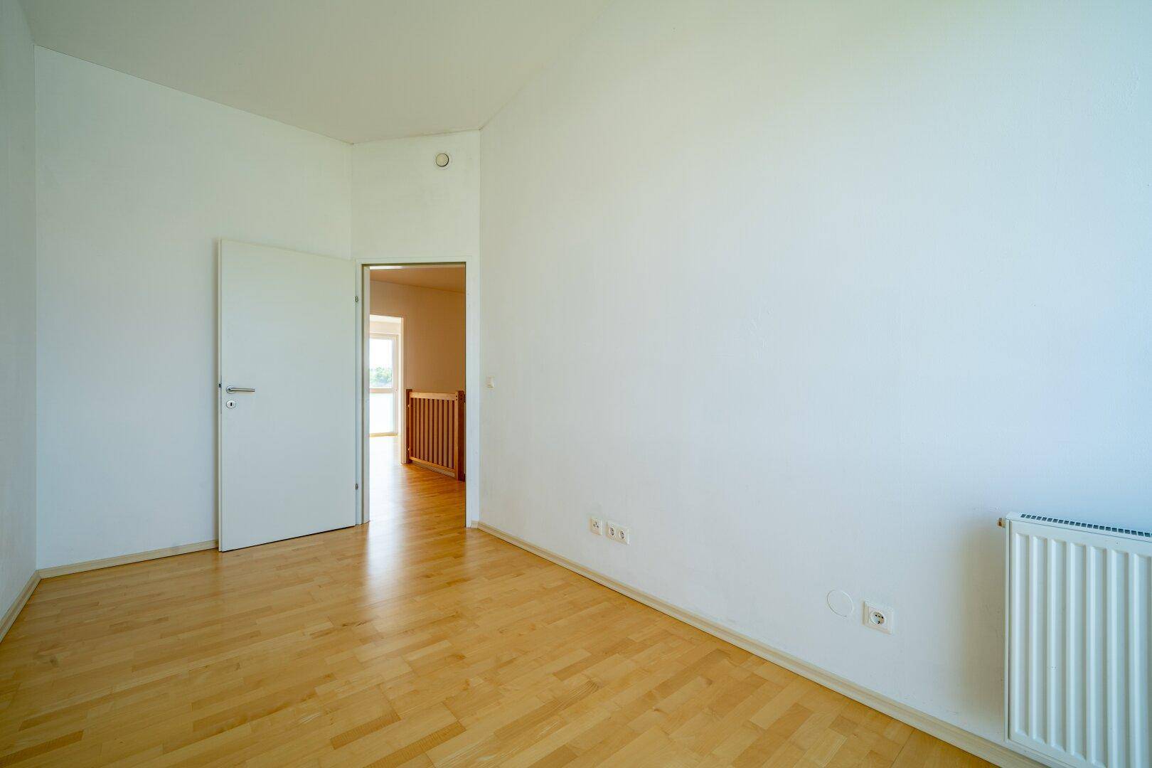 Helles Zimmer mit Parkettboden und Heizkörper, bereit für individuelle Gestaltung.