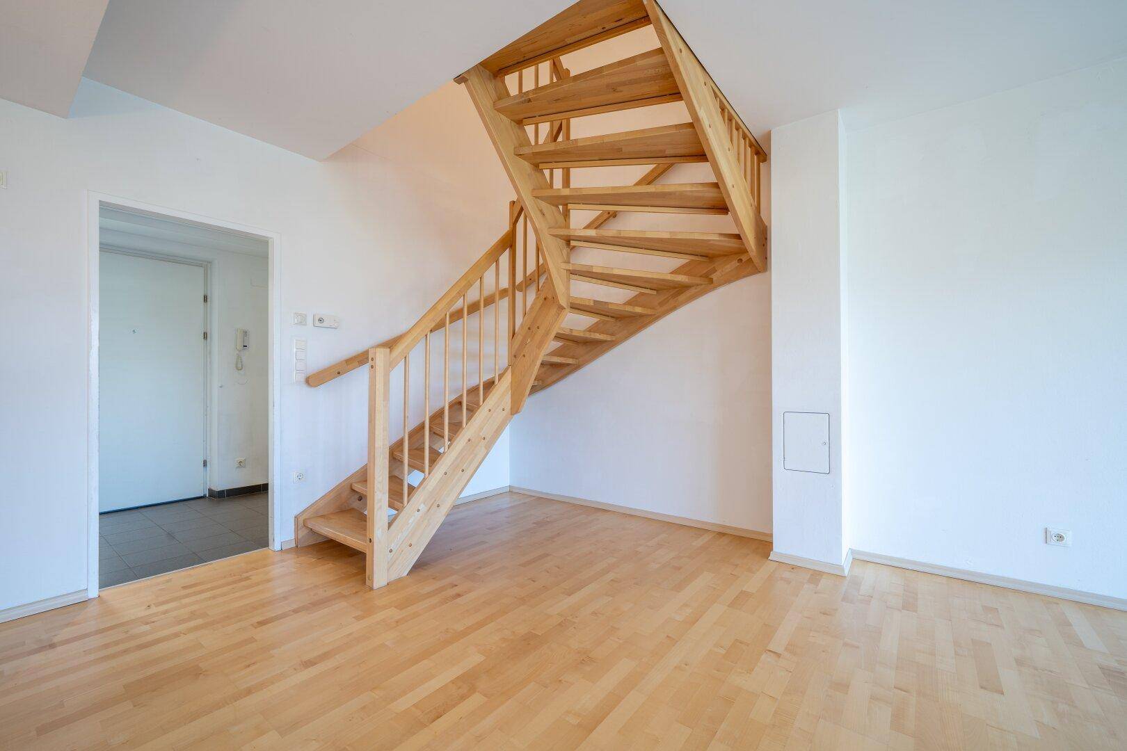 Detailansicht einer hellen Holztreppe im Wohnbereich mit Parkettboden.