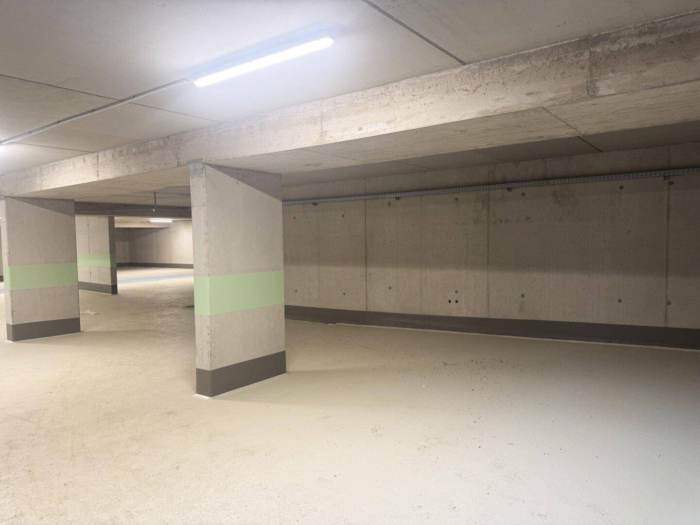 Geräumige Tiefgarage mit Betonpfeilern und hellen Böden, ideal für mehrere Fahrzeuge.