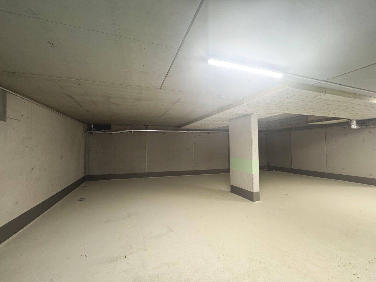 Sauberer und heller Bereich einer Tiefgarage mit Betonwänden und effizienter Beleuchtung.
