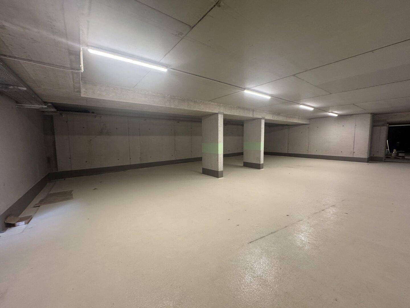 Weitläufige Tiefgarage mit mehreren Betonpfeilern und guter Ausleuchtung, bereit zur Nutzung.