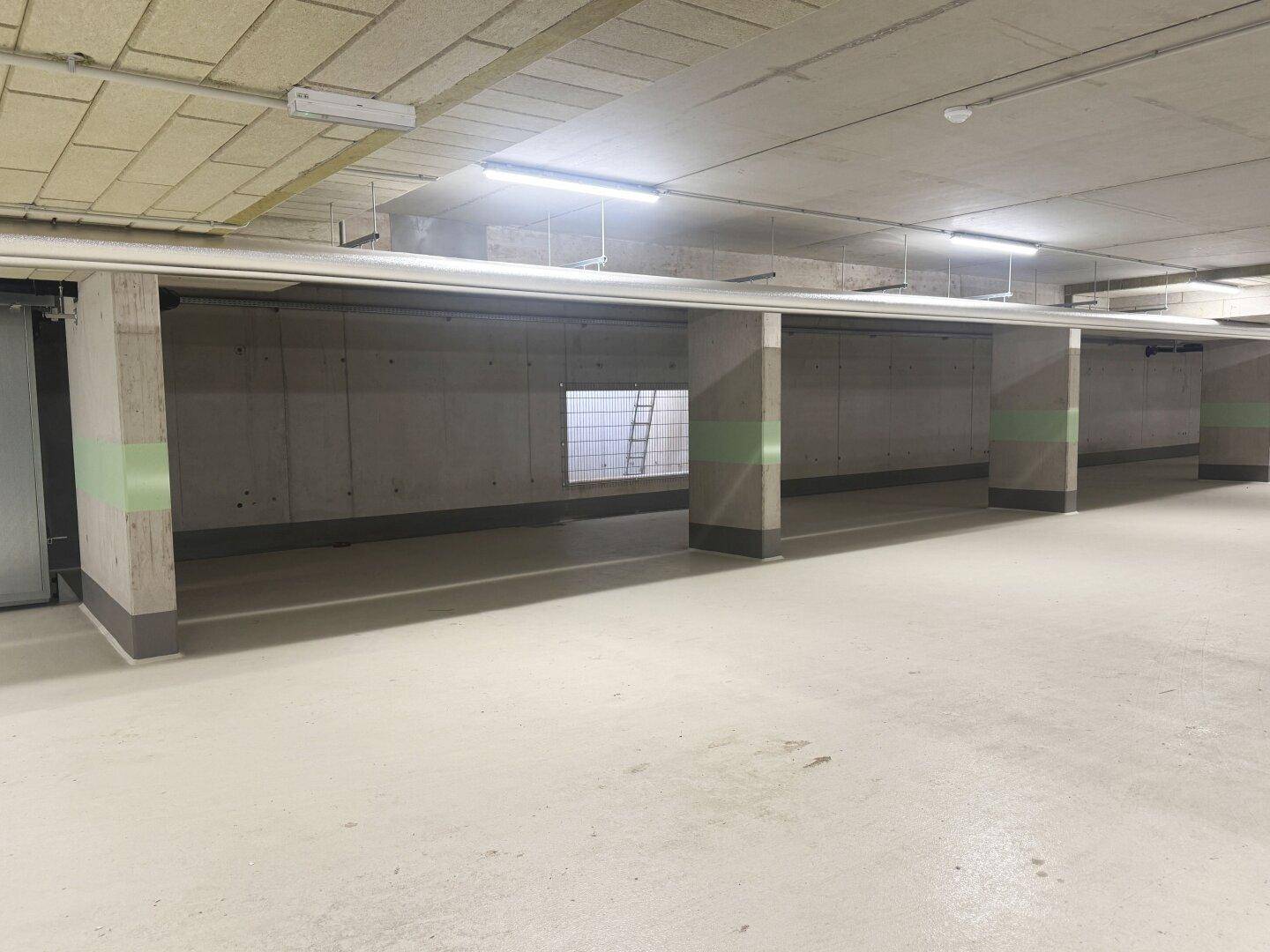 Moderne Tiefgarage mit Betonkonstruktion und klaren Markierungen, gut beleuchtet und zugänglich.