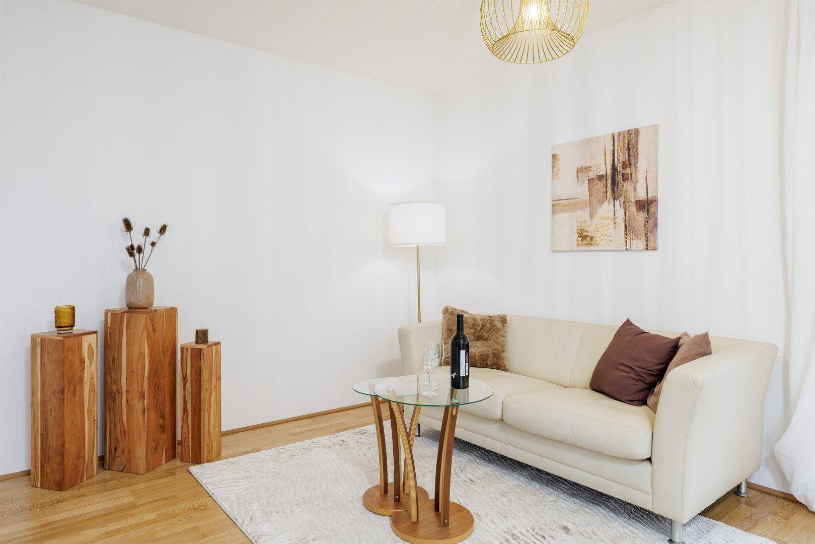 Gemütlicher Wohnbereich mit beigem Sofa, Holzboden und moderner Dekoration.