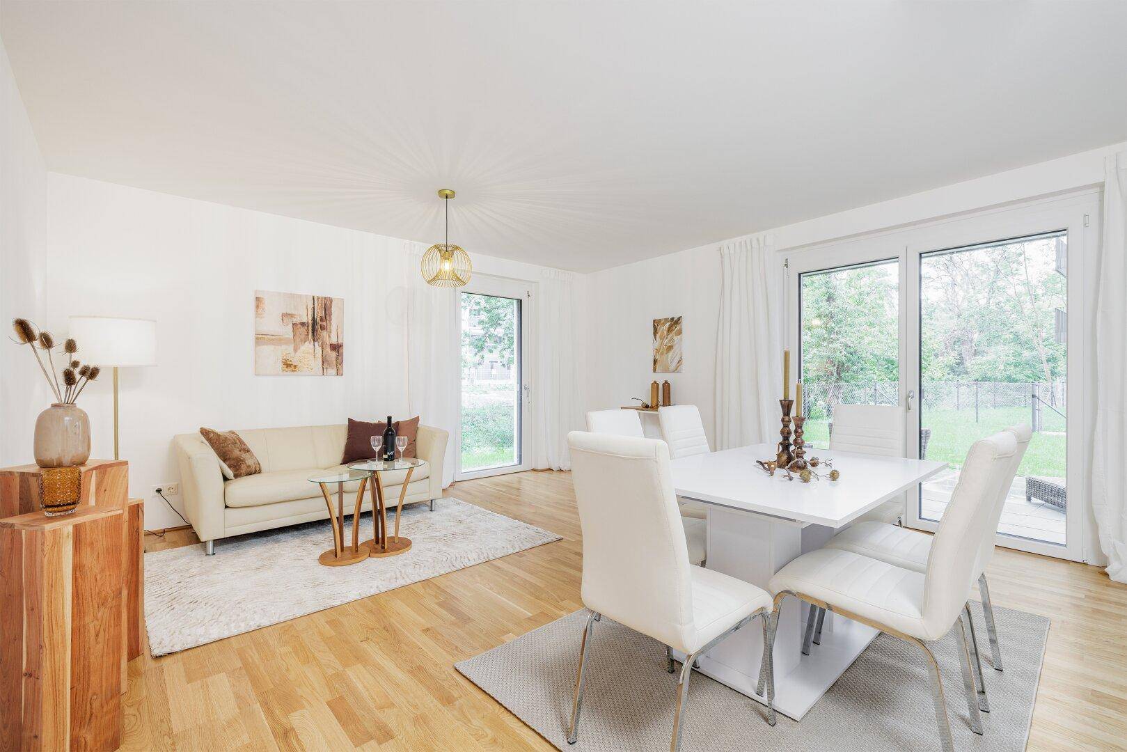 Helles Wohn-Esszimmer mit Holzboden, beigem Sofa und Zugang zum Garten.