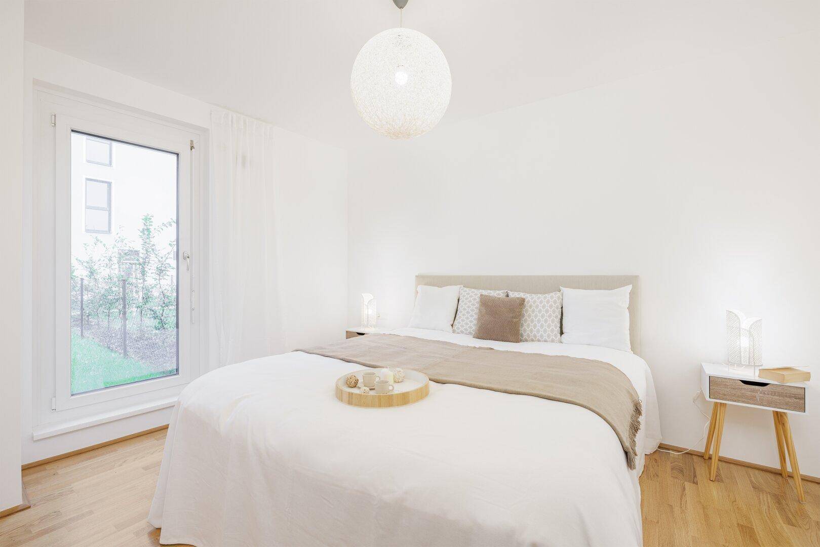 Helles Schlafzimmer mit Doppelbett, Holzboden und Zugang zum Garten.
