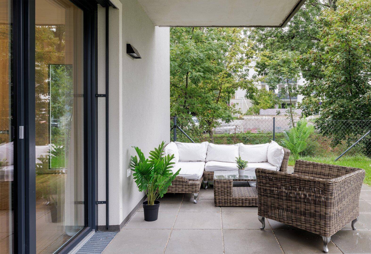 Gemütliche Terrasse mit Rattanmöbeln und Blick ins Grüne, ideal zum Entspannen.