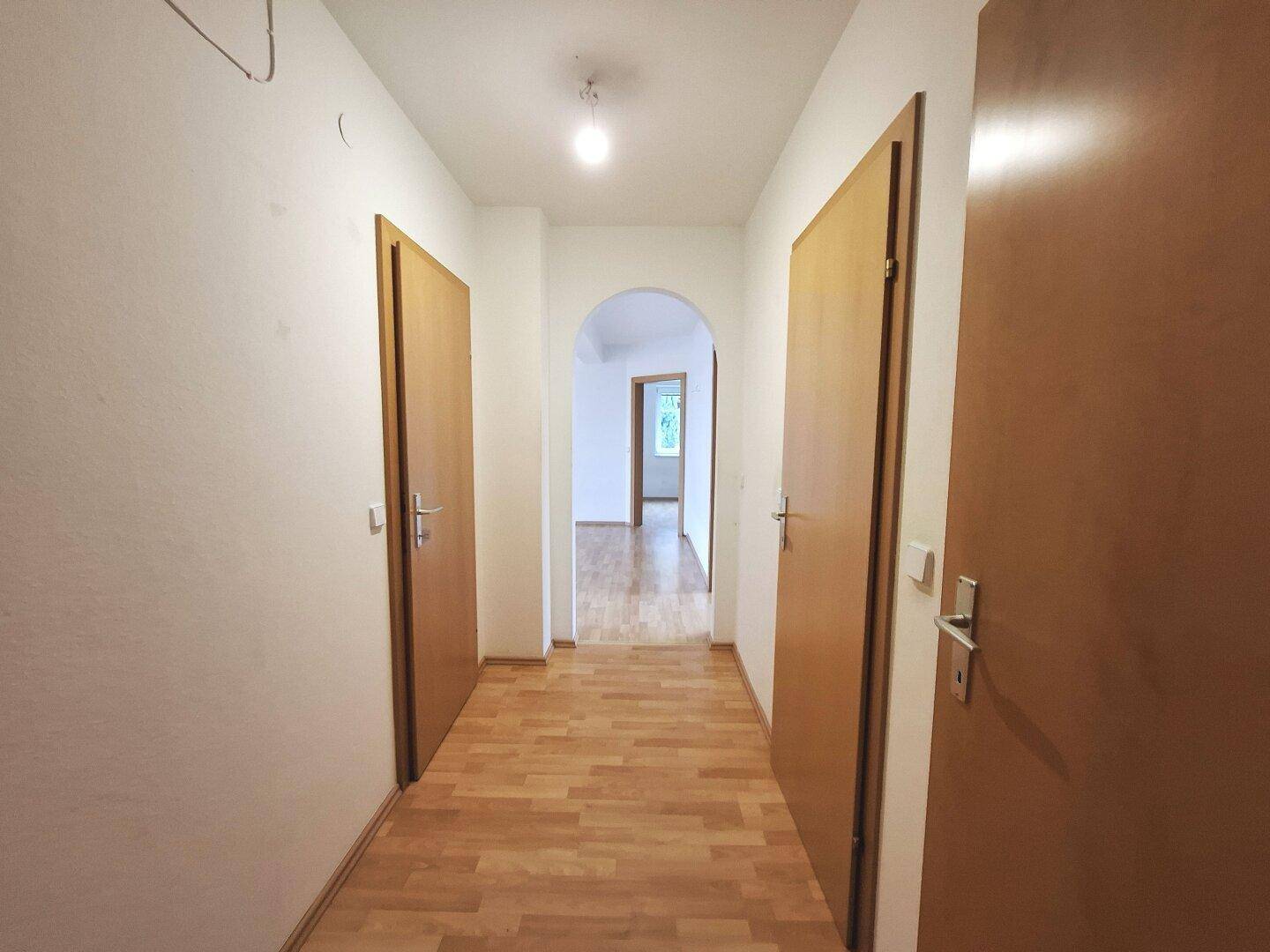 Heller Flur mit Laminatboden und mehreren Türen, die zu den angrenzenden Räumen führen.