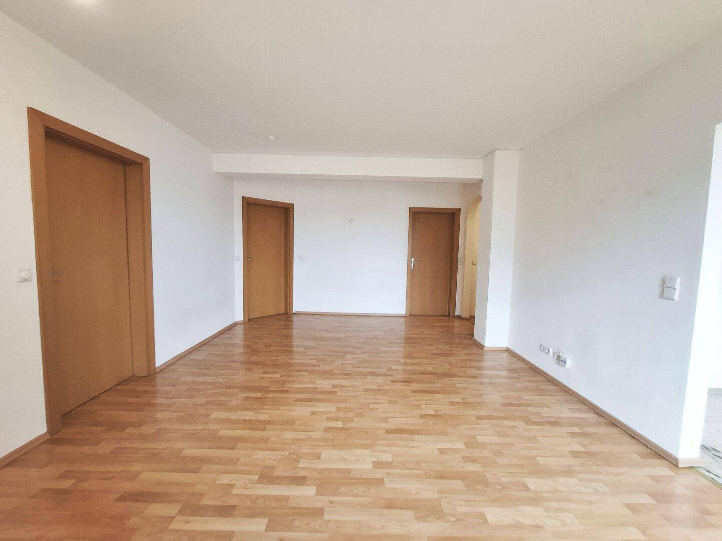 Heller Wohnraum mit Laminatboden und schlichten weißen Wänden, ideal für neue Einrichtungsideen.