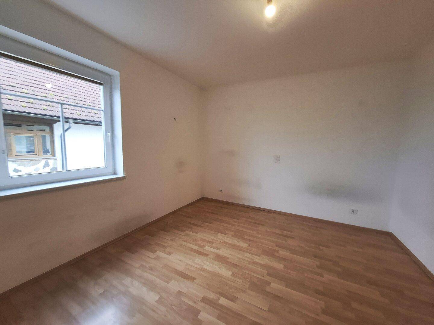 Helles Schlafzimmer mit Laminatboden und einem Fenster, das den Raum gut belichtet und eine angenehme Atmosphäre schafft.