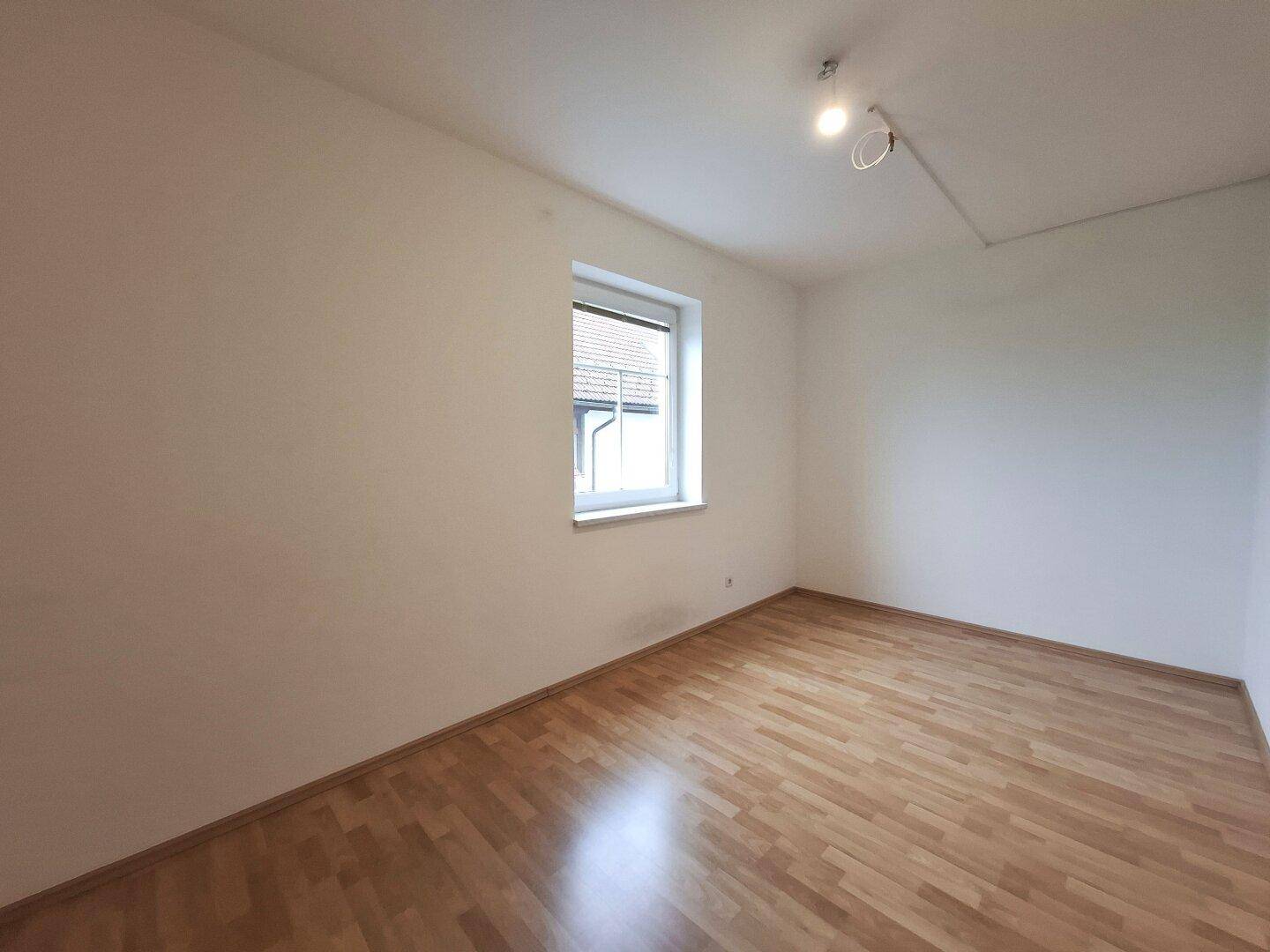 Schlafzimmer mit Laminatboden und einem Fenster, das für gute Belüftung sorgt und den Raum hell hält.
