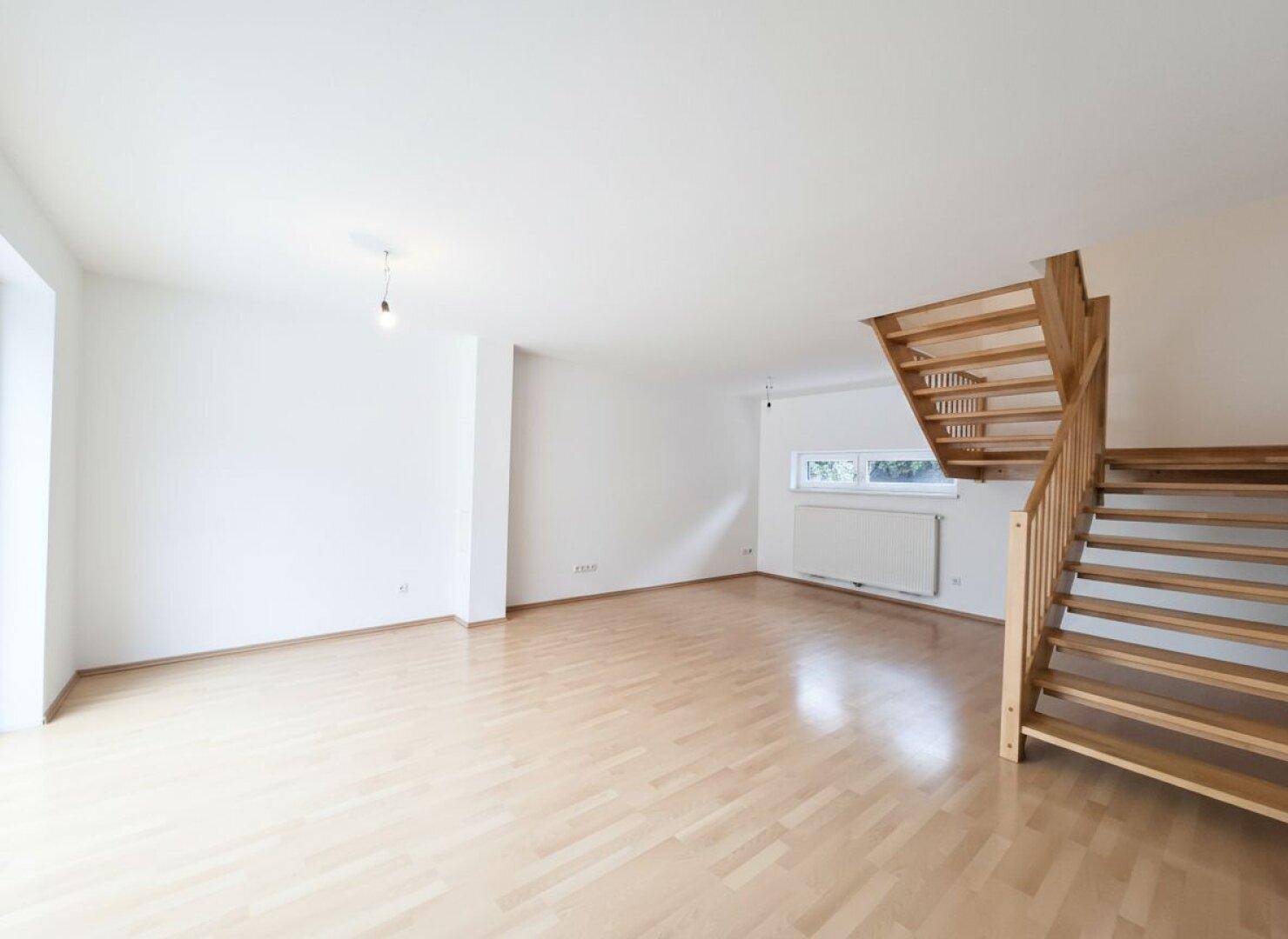 Geräumiger Wohnbereich mit heller Holztreppe und Parkettboden, ideal für offenes Wohnen.