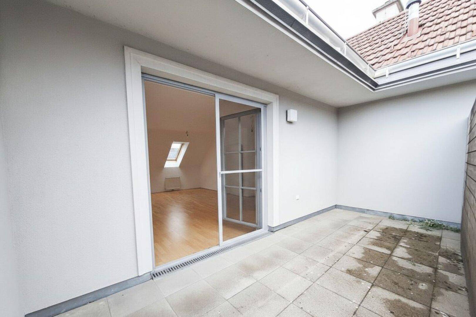 Balkon mit Schiebetürzugang zum Innenraum und Fliesenboden, bietet einen geschützten Außenbereich.