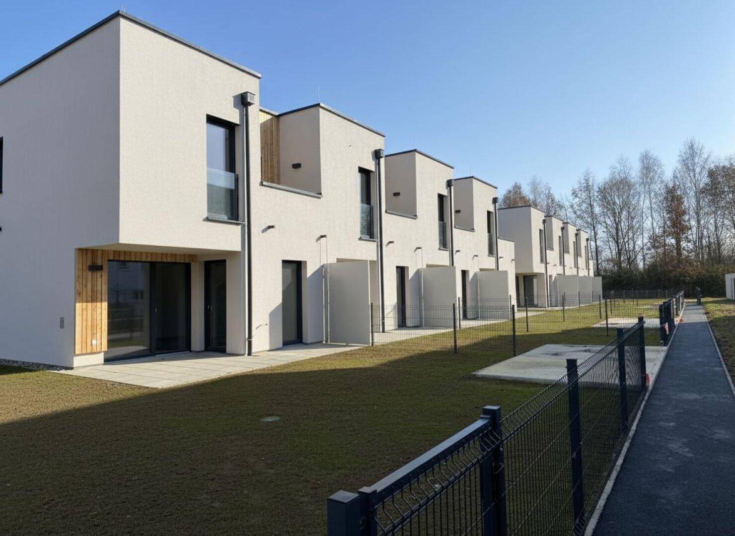 Rückseite der Reihenhäuser mit privaten Gärten, Terrassen und großen Fenstern zum Grünbereich.