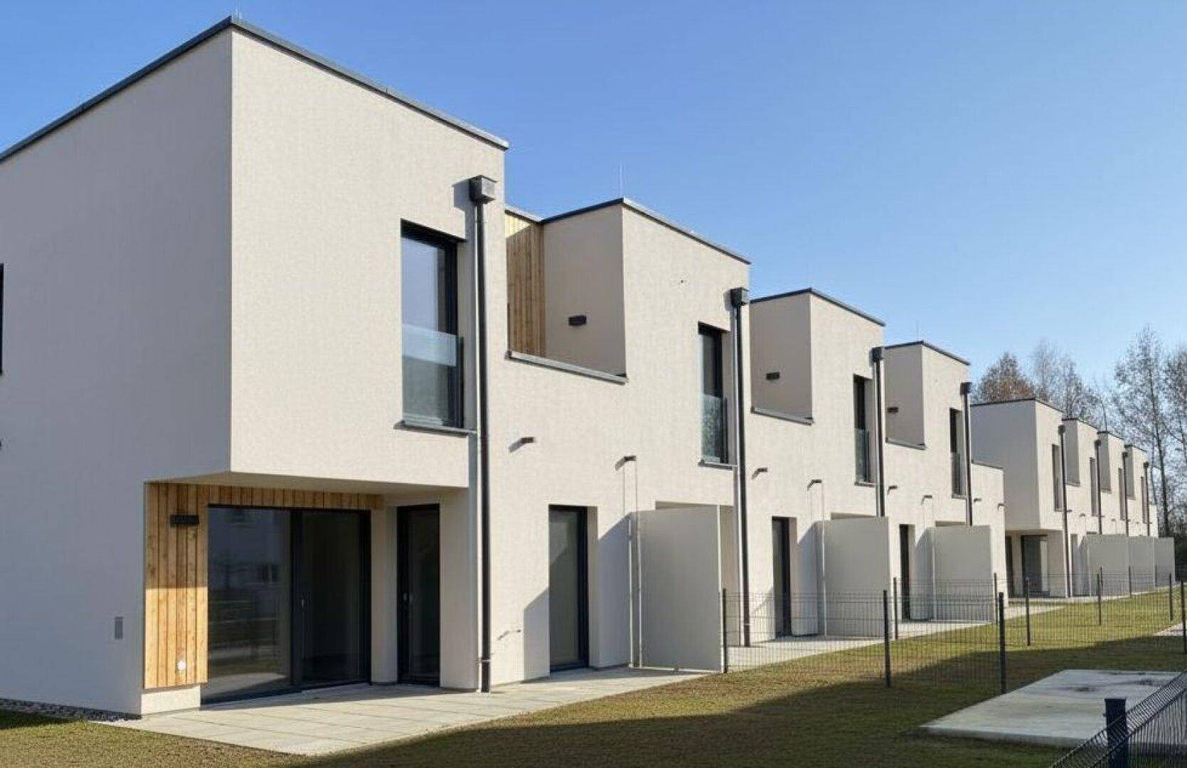 Helle Reihenhäuser mit privaten Gärten und Terrassen, ideal für entspannte Stunden im Freien.