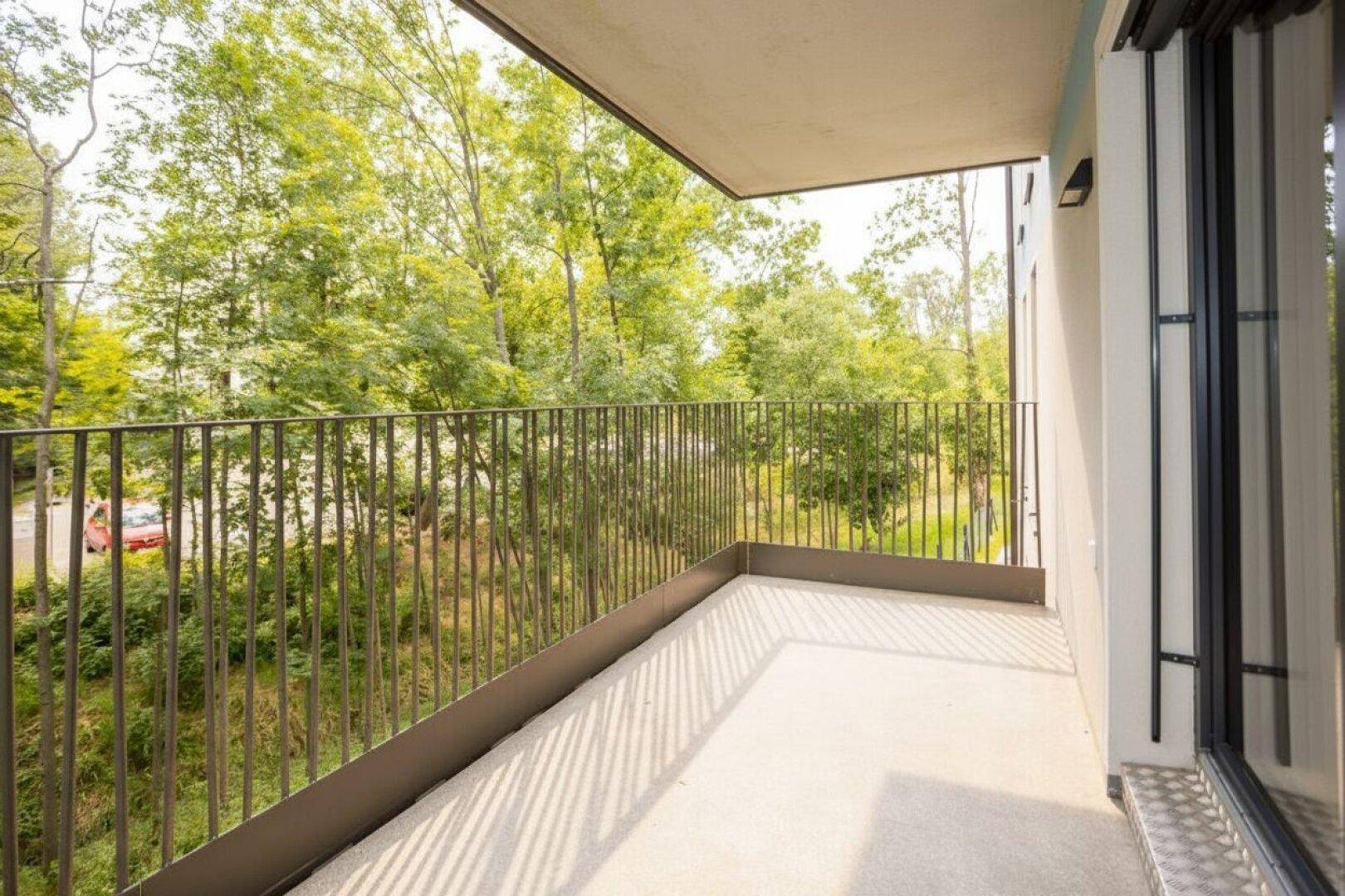 Heller Balkon mit Metallgeländer und Blick ins Grüne, ideal zum Entspannen.