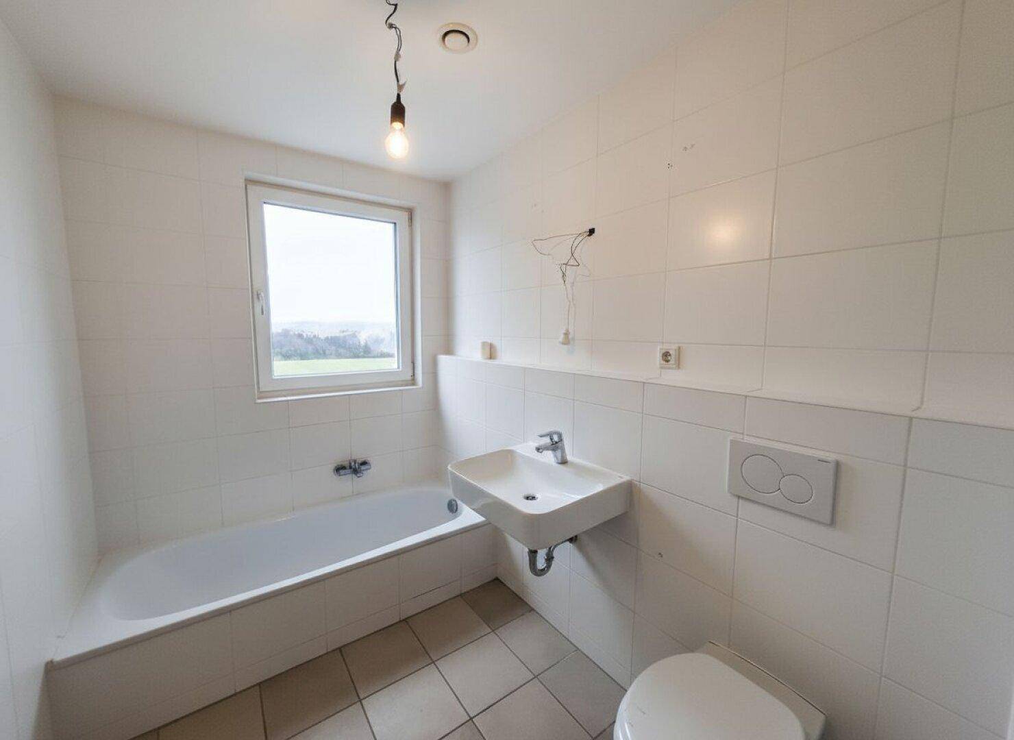 Badezimmer mit Badewanne, Waschbecken, Toilette und Fenster für natürliche Belüftung.