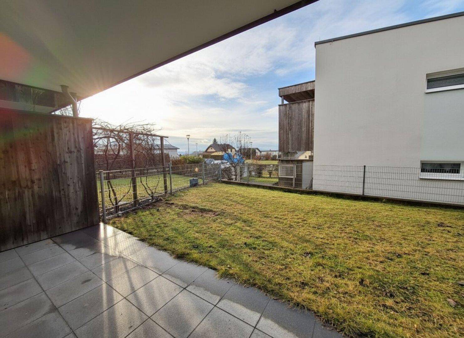 Sonniger Garten mit Terrasse und Blick auf die umliegende Landschaft und Nachbarschaft.
