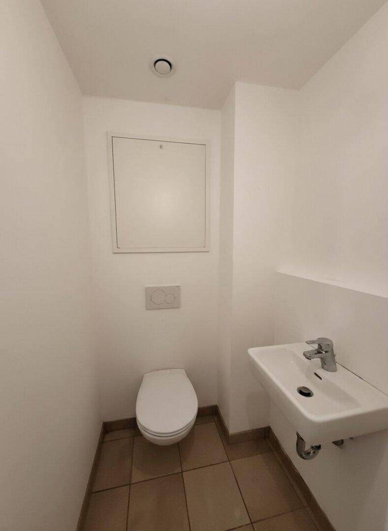 Gäste-WC mit Waschbecken und Toilette, ausgestattet mit Fliesenboden.
