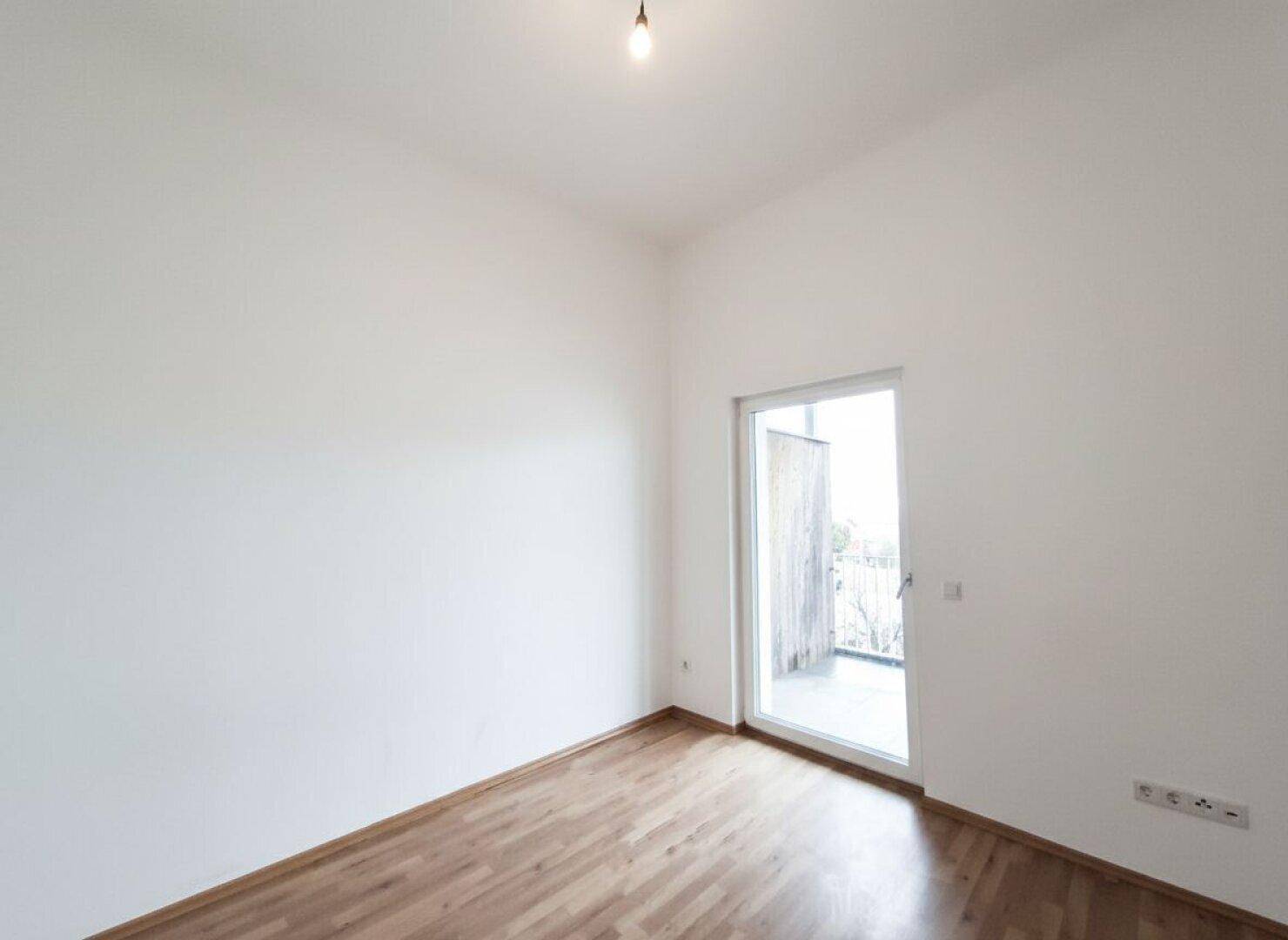 Schlafzimmer mit Parkettboden und Zugang zu einem weiteren Balkon, der frische Luft bietet.