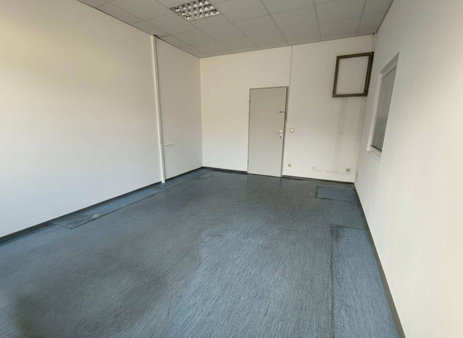 Leerer Raum mit einer Tür und einem kleinen Fenster, ideal für ein Einzelbüro oder Lager.
