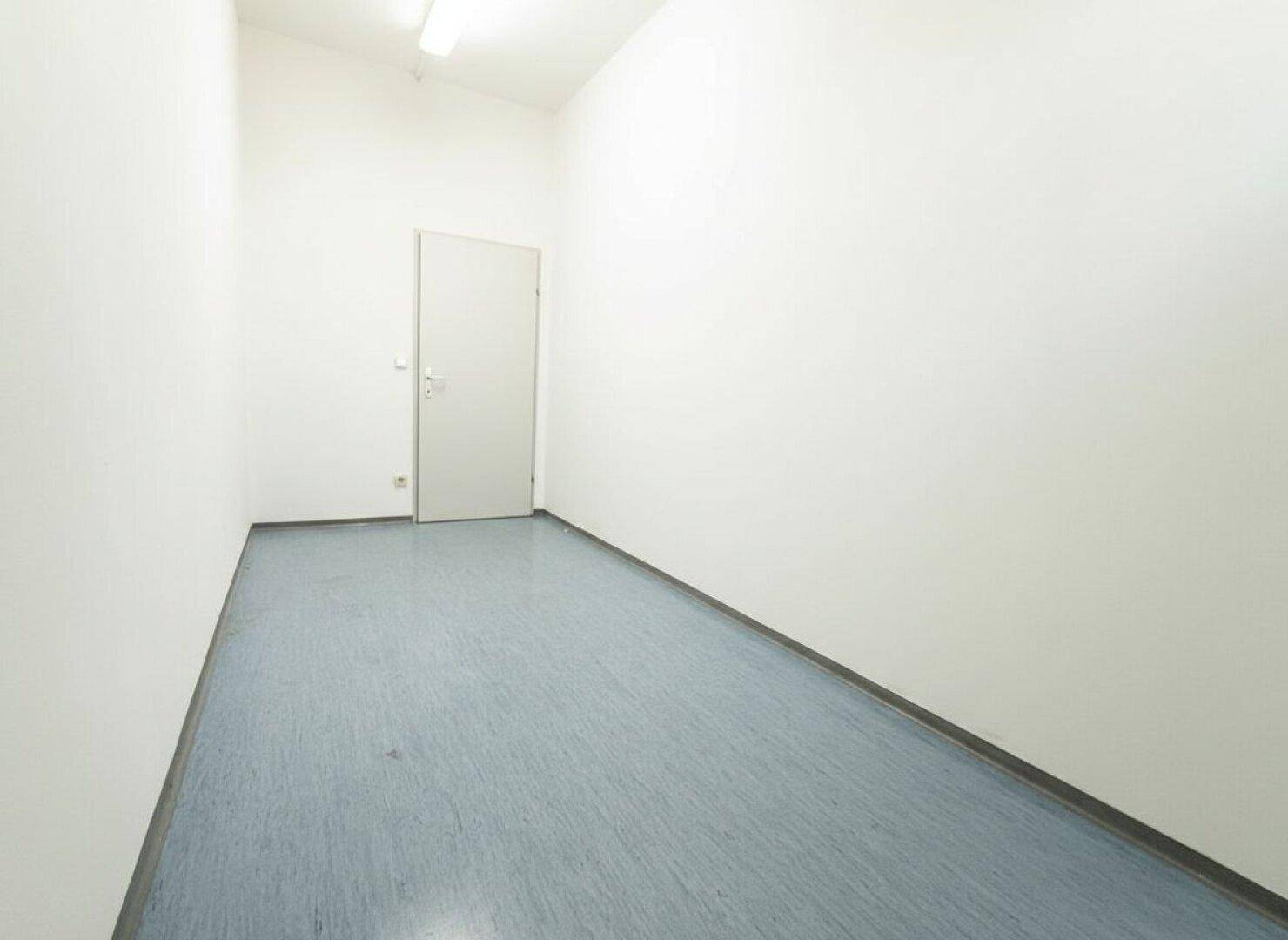 Kleiner, leerer Raum mit einer Tür und einfachem Boden, nutzbar als Abstellkammer oder Serverraum.