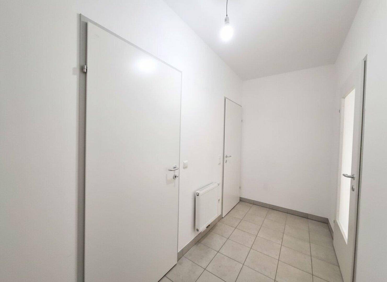 Heller Eingangsbereich mit Fliesenboden und mehreren Türen zu angrenzenden Räumen.