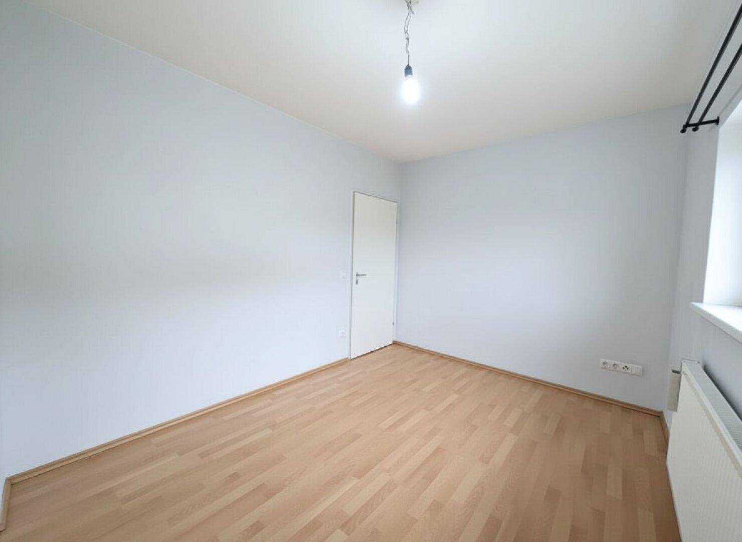 Neutral gestaltetes Zimmer mit Parkettboden und Fenster, vielseitig nutzbar.