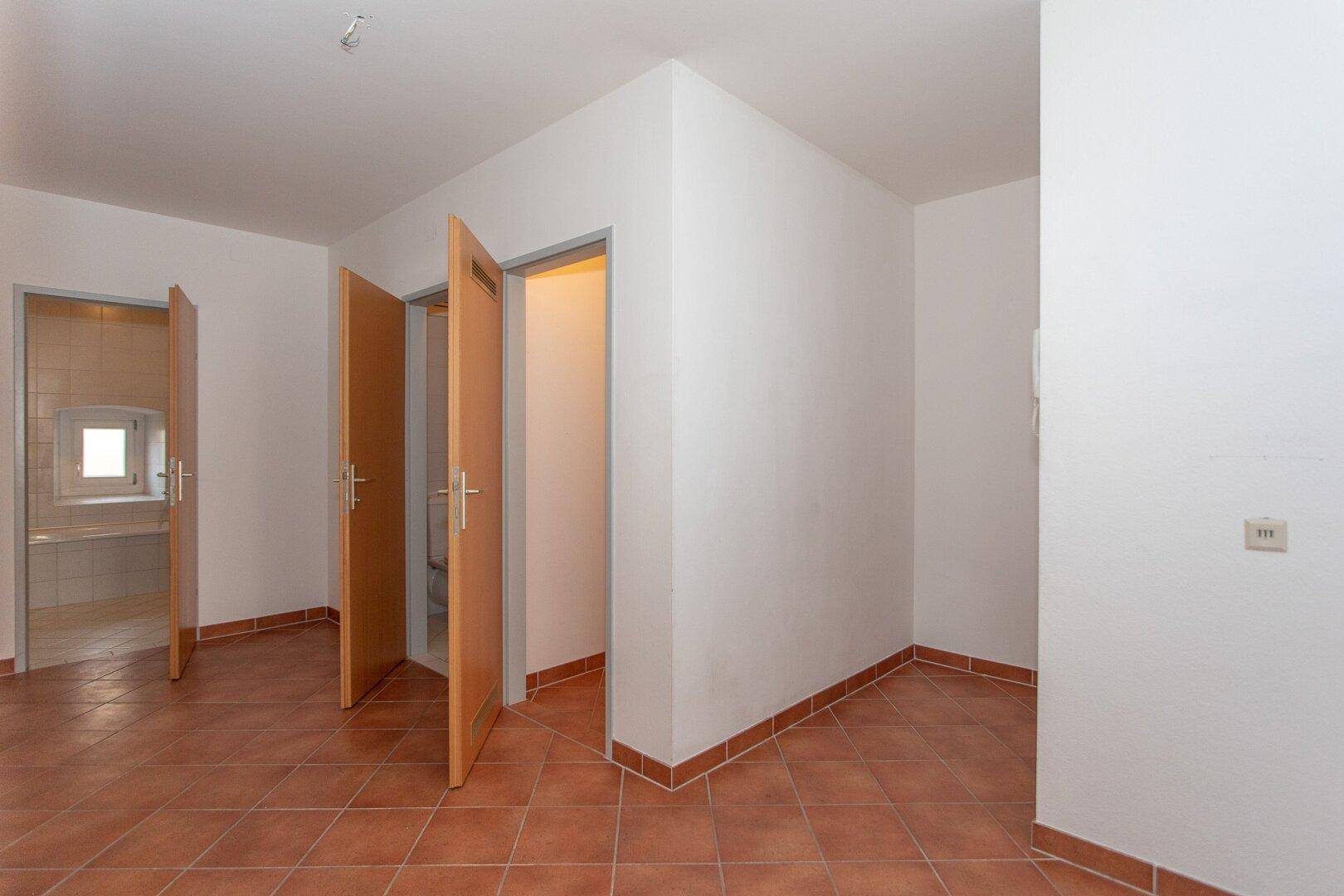 Geräumiger Flur mit Terrakottafliesen und Zugang zu mehreren Zimmern, hell und einladend.