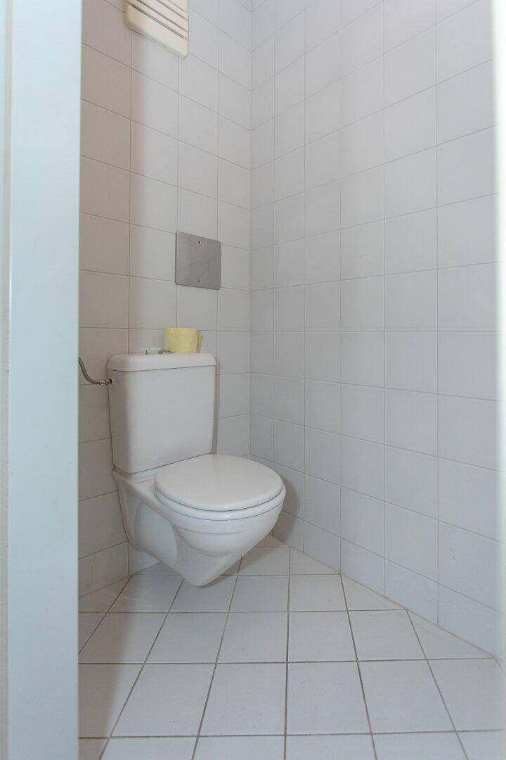Kleines, gefliestes WC mit wandhängender Toilette und Ablagefläche, funktional und sauber.