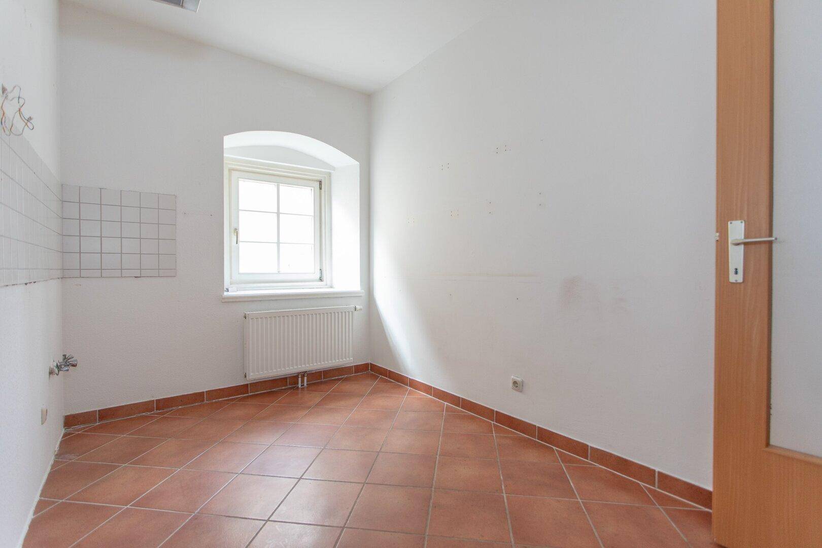 Helle Küche mit Terrakottafliesen und Fenster, bietet Potenzial für eine moderne Küchengestaltung.