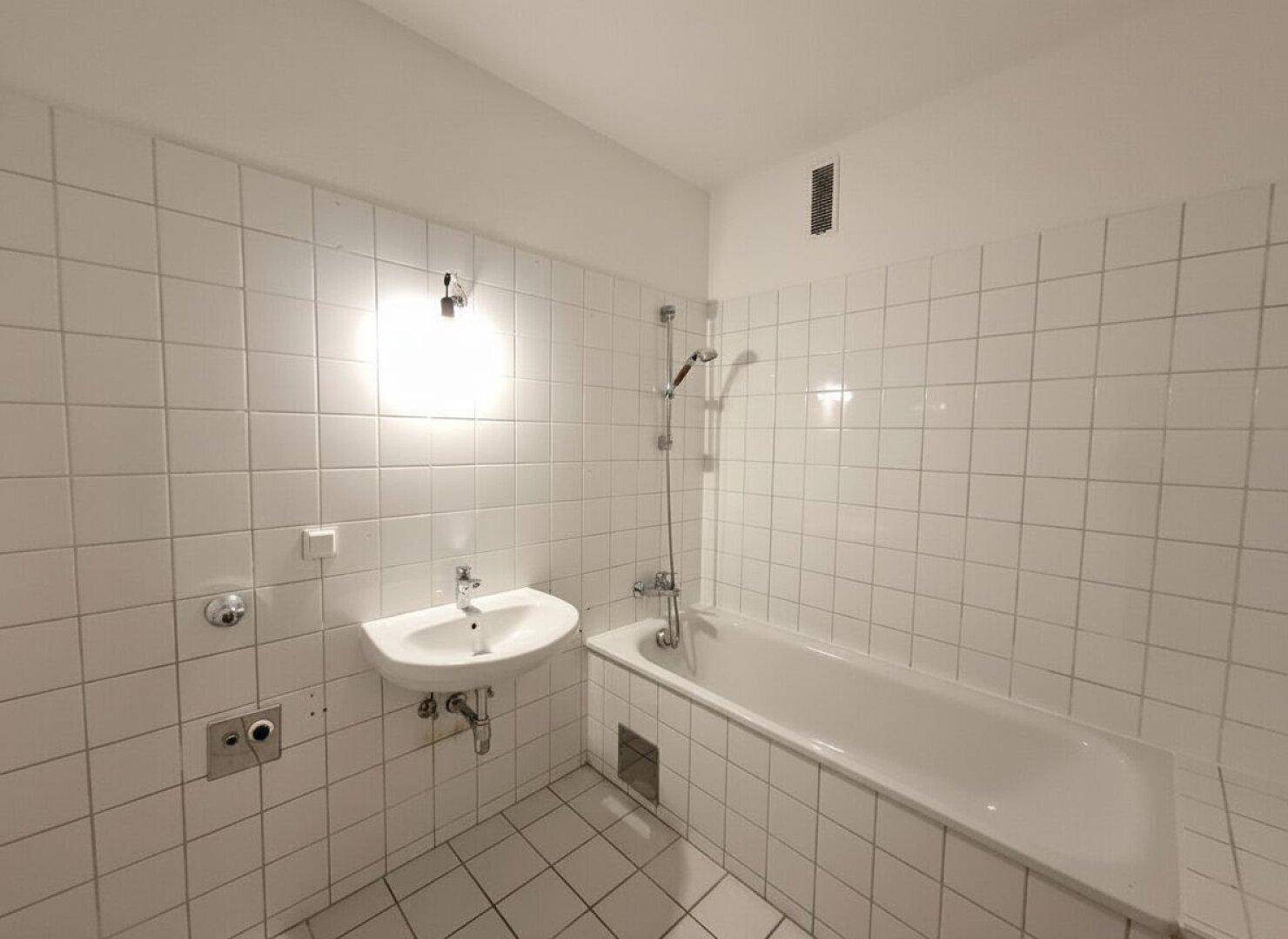 Separates WC mit weißen Fliesen und Standard-Toilette, funktional und schlicht.