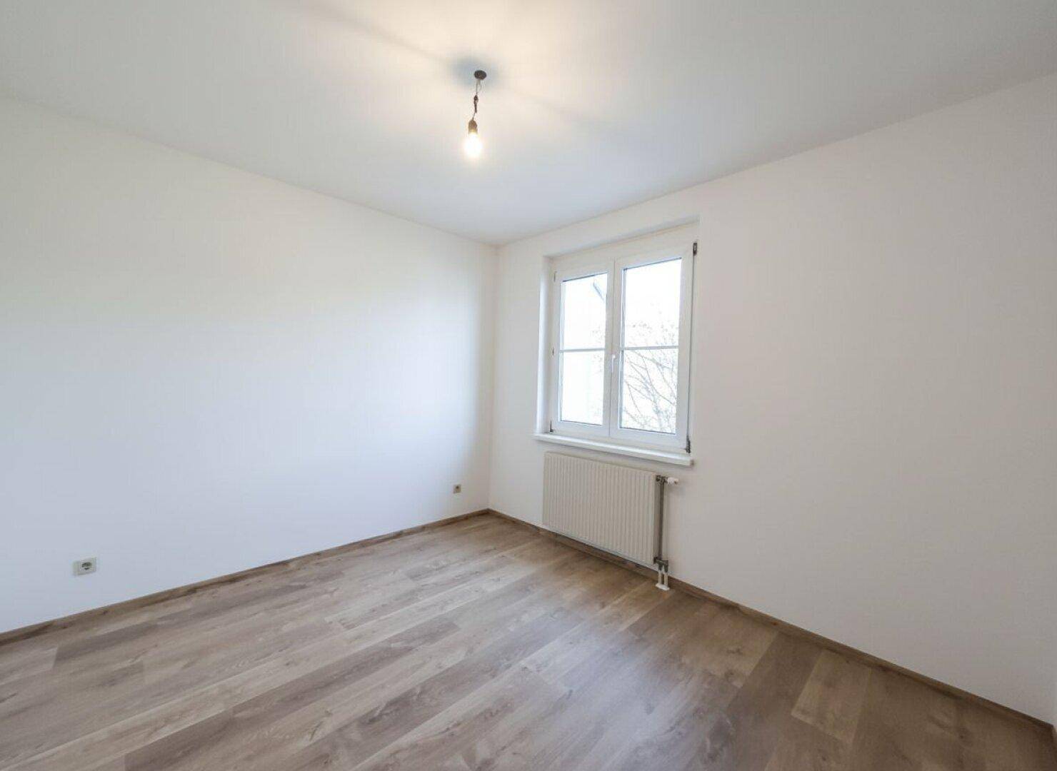 Geräumiges Zimmer mit Laminatboden und weiß gestrichenen Wänden, vielseitig nutzbar.