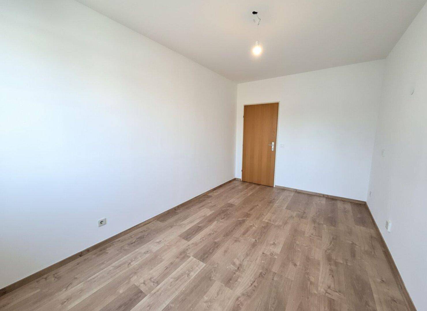 Helles Badezimmer mit weißen Fliesen, Badewanne und Holztür, sauber und gepflegt.