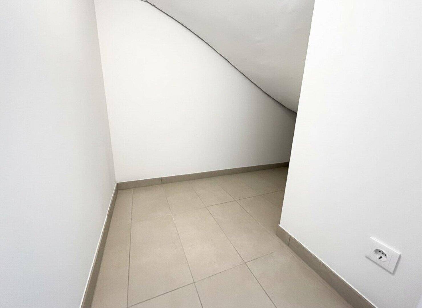 Praktischer Abstellraum unter der Treppe mit Fliesenboden, ideal für zusätzlichen Stauraum.
