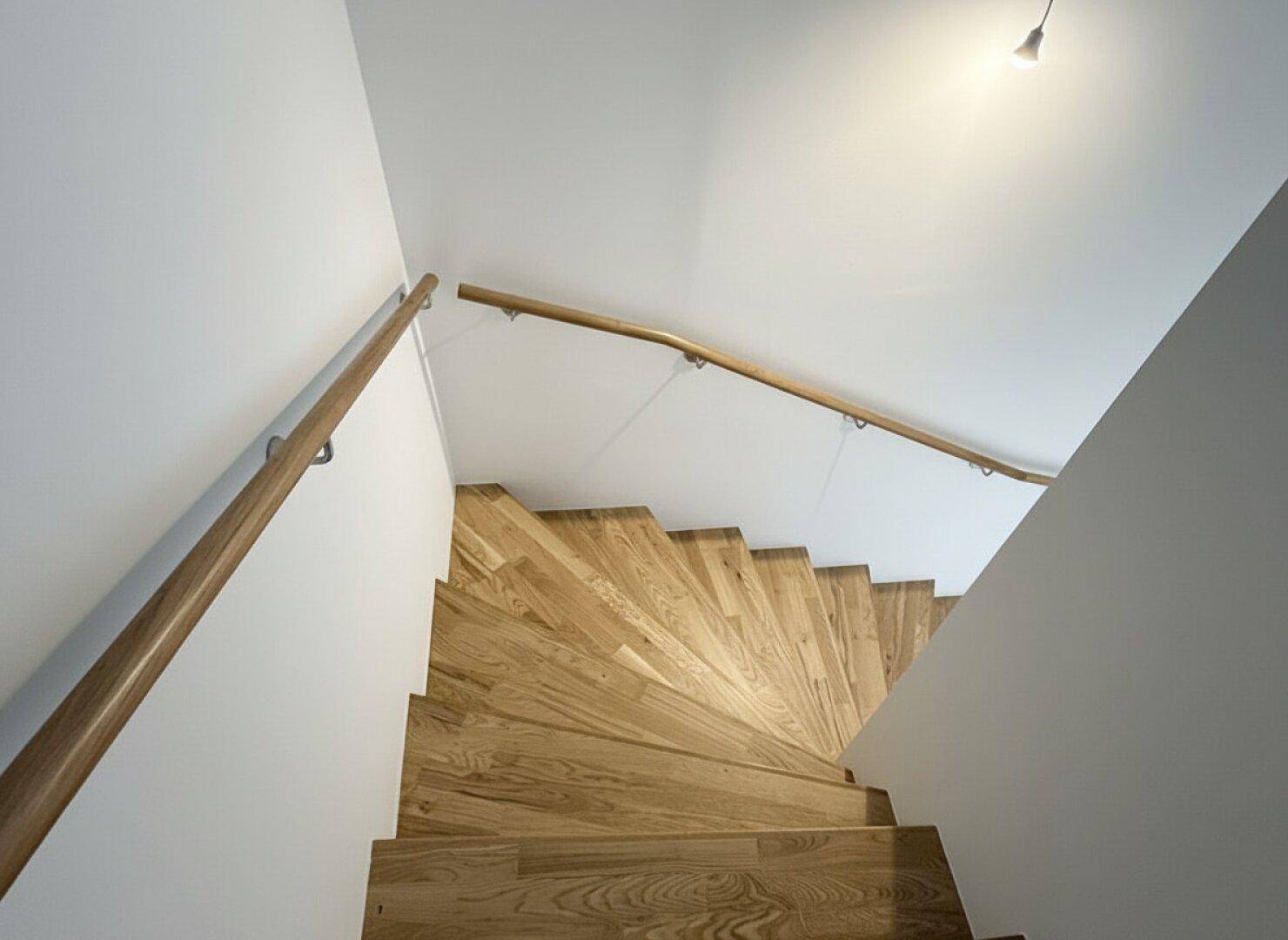 Elegante Holztreppe mit Handlauf, die die verschiedenen Etagen des Hauses miteinander verbindet.