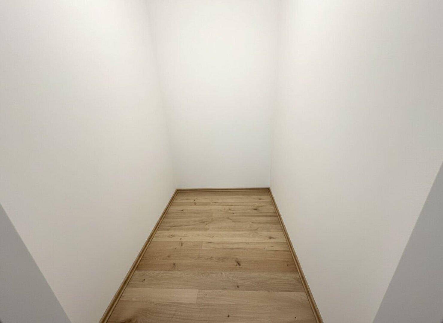 Kleiner, leerer Abstellraum mit Laminatboden und weißen Wänden.