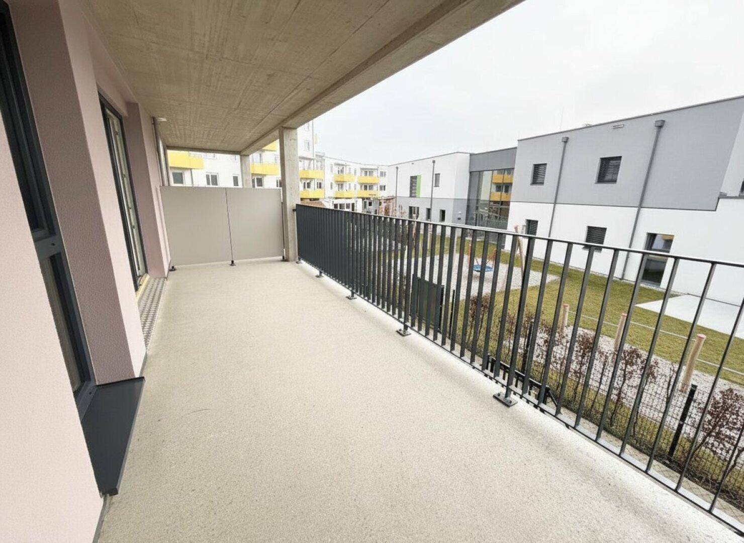 Geräumiger Balkon mit Blick auf den Innenhof und die umliegenden Neubauten.