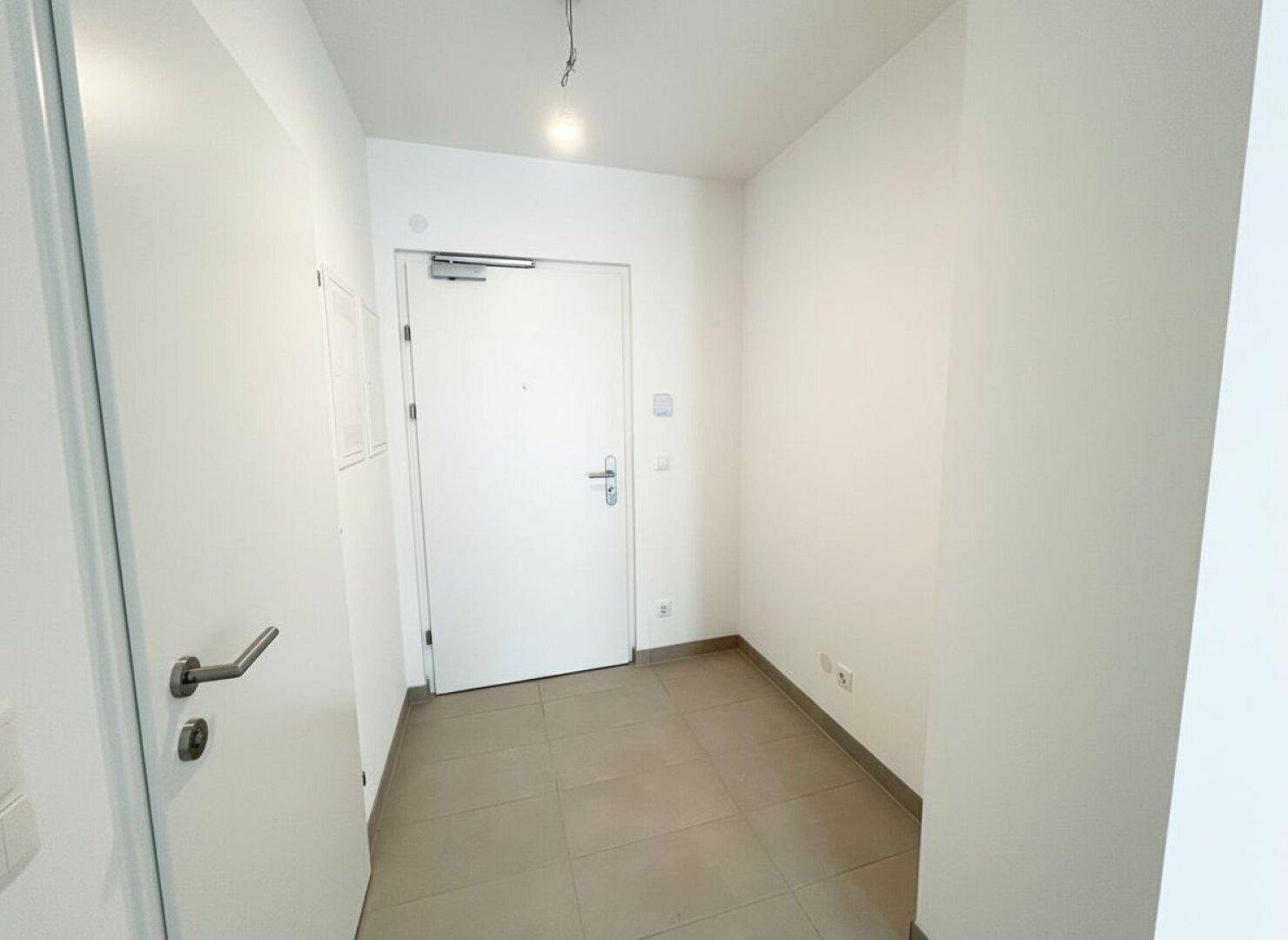 Heller Eingangsbereich mit Fliesenboden und weißer Eingangstür.
