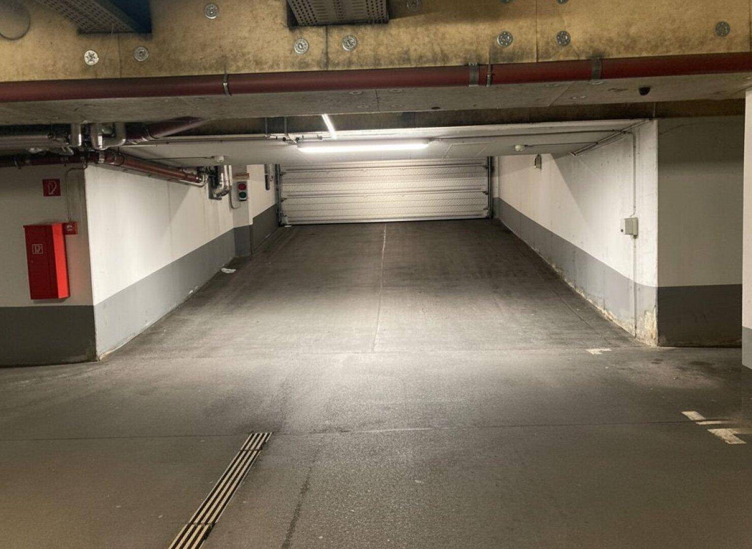 Innenansicht der Tiefgaragenrampe mit geschlossener Rolltor und Brandschutzvorrichtung an der Wand.