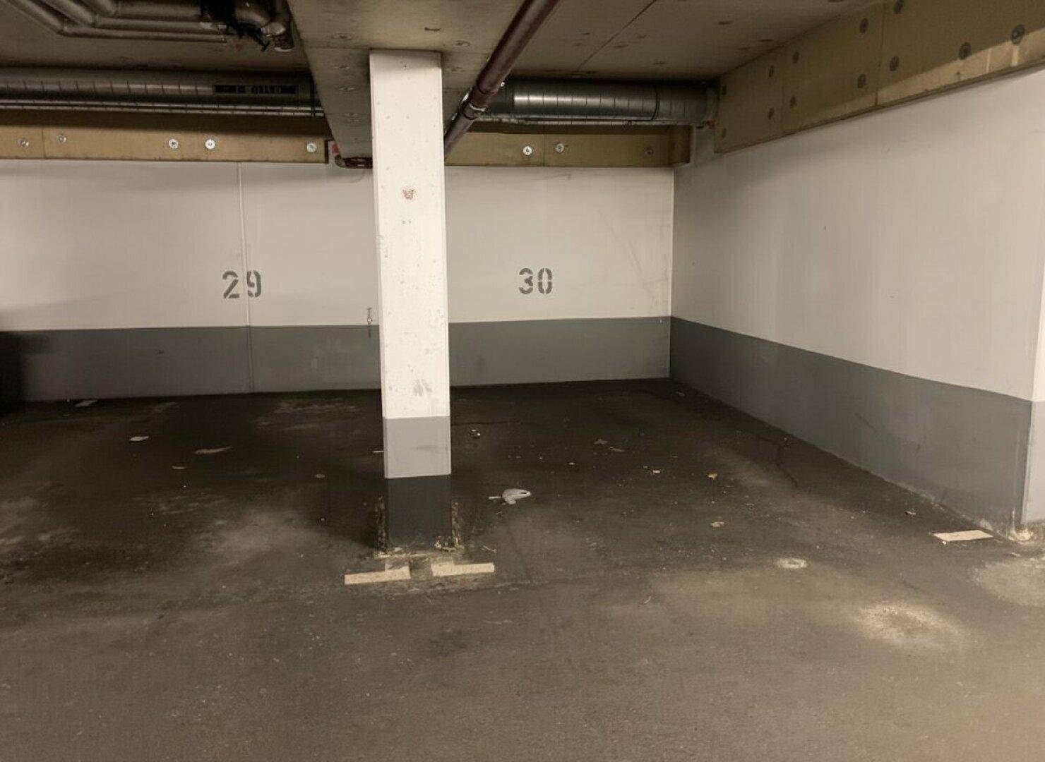 Tiefgaragenstellplätze 29 und 30 mit Betonstütze und sichtbaren Leitungen an der Decke.