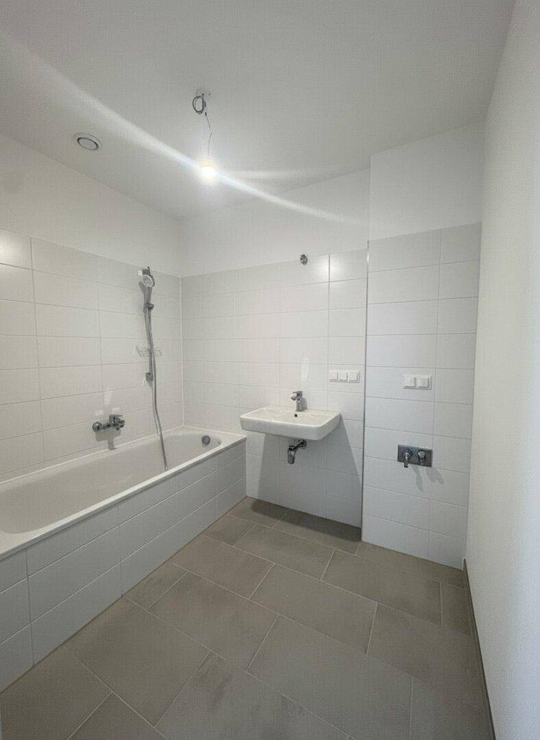 Modernes Badezimmer mit Badewanne, Waschbecken und weißen Wandfliesen.