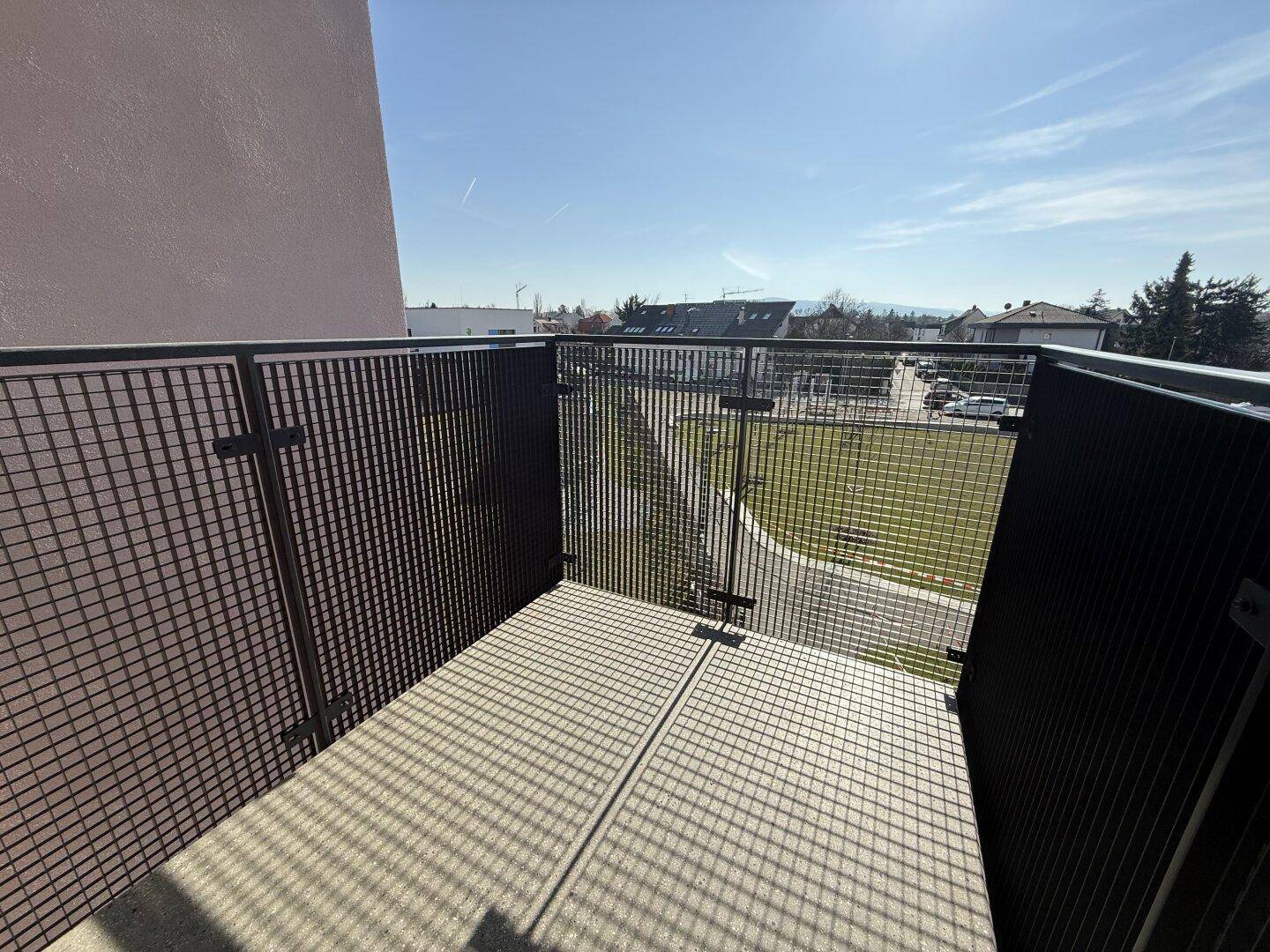 Moderner Balkon mit Gittergeländer und Blick auf die grüne Umgebung, perfekt für entspannte Stunden.