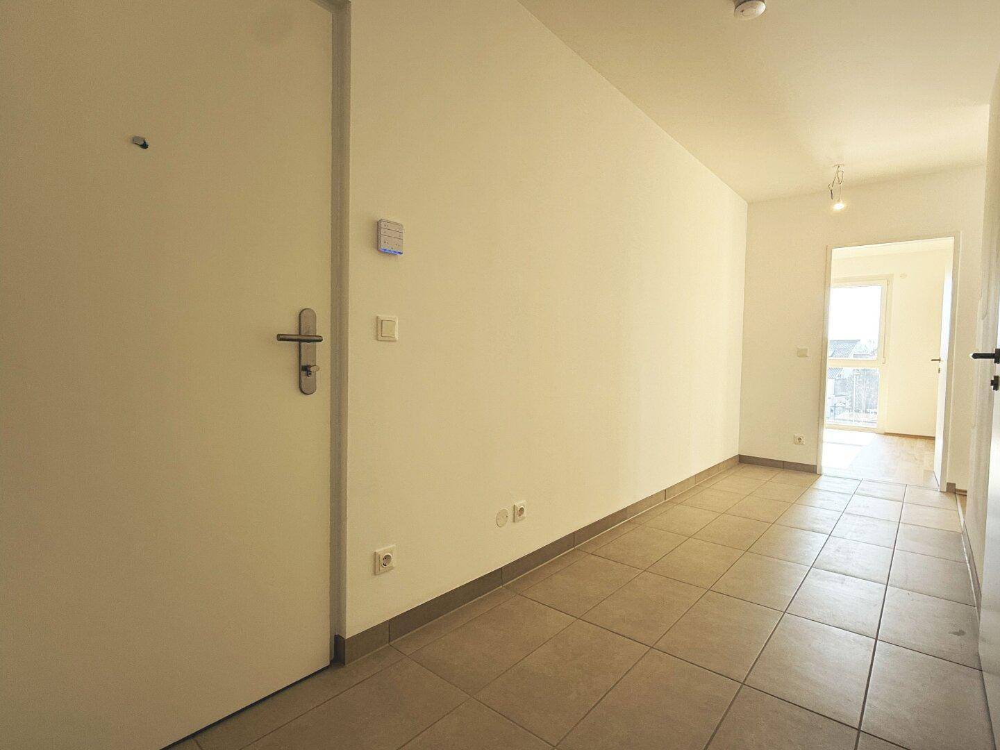 Moderner Flur mit Fliesenboden und heller Beleuchtung, bietet Zugang zur Wohnung und den Zimmern.
