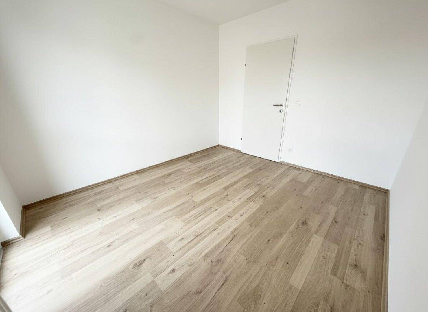 Kleiner, heller Raum mit Laminatboden und weiß gestrichenen Wänden, vielseitig nutzbar.