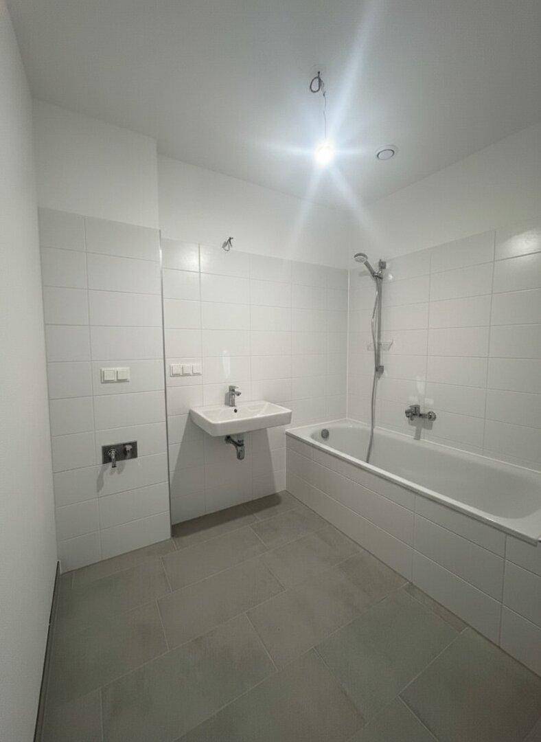 Modernes Badezimmer mit Badewanne, Duschfunktion und weiß gefliesten Wänden.